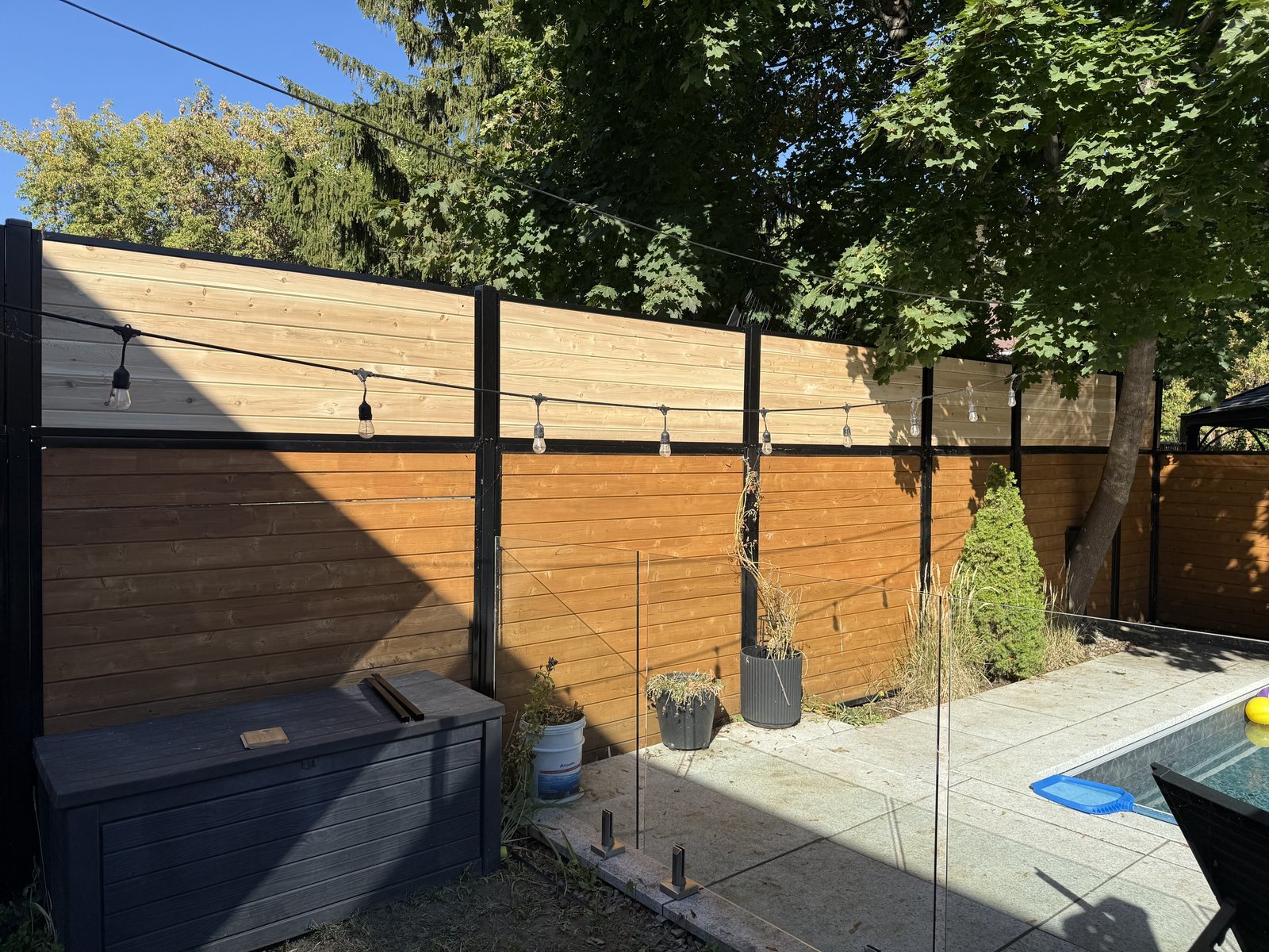 Clôture de bois deux tons à cadre d'aluminium noir avec panneaux de verre trempé près de la piscine