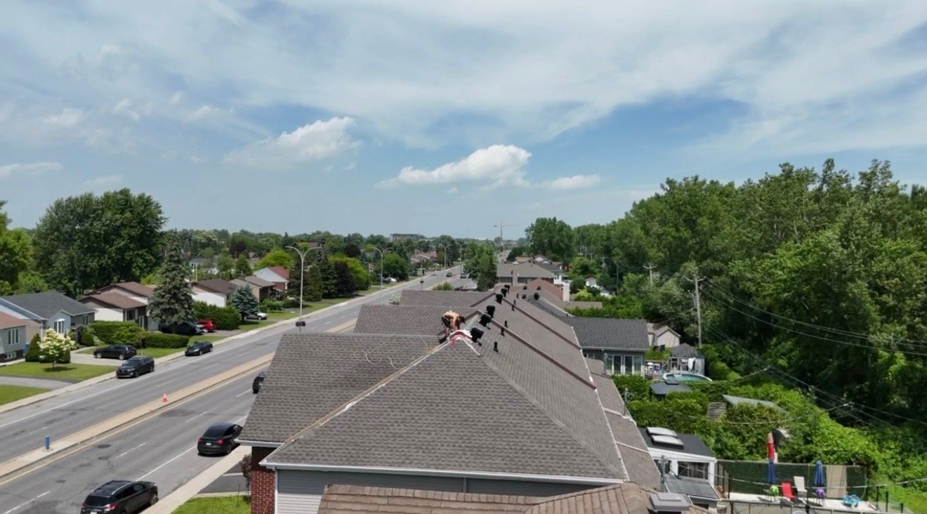 Vue aérienne par drone de l'équipe de couvreurs sur les toits de maisons en rangée le long du boulevard